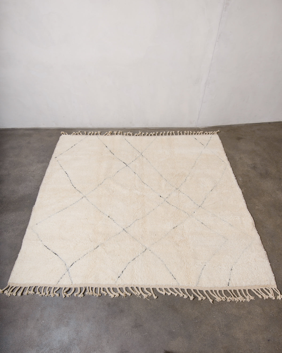 Berberlin Beniourain rug with minimal black line design laying flat on concrete floor.